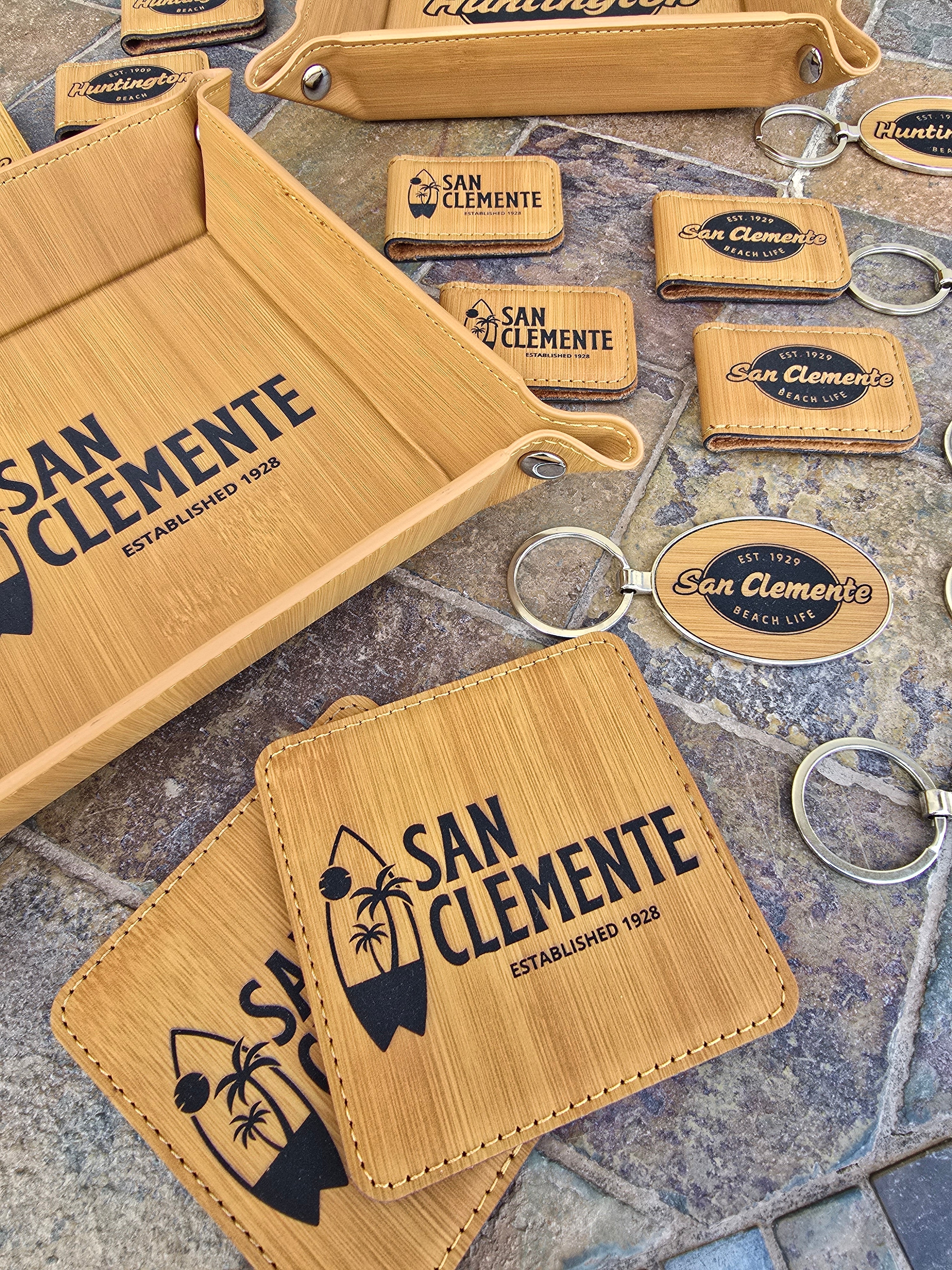 Assortment of custom souvenir merchandise, including keychains, can koozies, coasters, bottle openers, and locally inspired gifts.